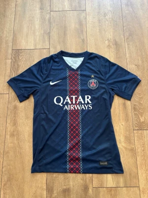 Paris Saint-Germain (PSG) Hemmatröja - Strl M ⚽🔥 - Snygg PSG-hemmatröja med Qatar Airways-sponsor och klassiska detaljer på ärmarna. Skön passform och perfekt för matchdagar eller till vardags!  Märke: Nike  Lag: Paris Saint-Germain (PSG)  Storlek: M  Skick: Fint skick Skickas spårbart eller hämtas enligt överenskommelse. Skicka ett DM vid intresse eller frågor! 🤝 