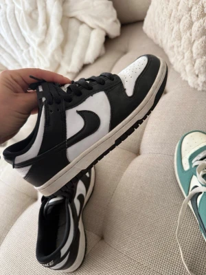 Nike Dunk Low svart/vit sneakers - Säljer ett par Nike Dunk Low sneakers i svart och vitt läder. Klassisk låg modell med svart Swoosh, svart snörning och vit tåbox med perforeringar. Tidlös streetstil som passar till det mesta. Saknar innersula 