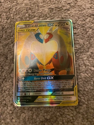 Latias & Latios GX Pokémonkort - Säljer ett holografiskt Latias & Latios GX TAG TEAM Pokémonkort med 250 HP. Kortet har en snygg guldram och motivet visar Latias och Latios i ett hjärta. Perfekt för samlare eller Pokémonfans som vill utöka sin samling.