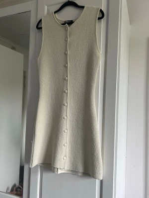 Beige klänning  - Stilren beige klänning från Gina Tricot med rund halsringning och knappar framtill. Klänningen har en lätt strukturerad yta och är ungefär i knän längd. Aldrig använd!