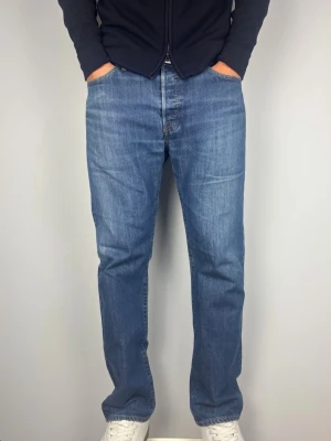 Levis 501 Jeans Vintage - Levis 501, raka jeans. Färg: Blå | Modell: 501 | Storlek: W34 L32 |. Killen på bilden har fått dragit ner byxorna en del i syfte att visa passform, kolla måtten nedan för att se om dem passar! Mycket gott skick, inga skador eller slitningar. Mått: A: 43 cm B: 102 cm C: 20,5 cm D: 29 cm Tveka inte att höra av dig minsta fråga eller fundering! Skickas snabbt!
