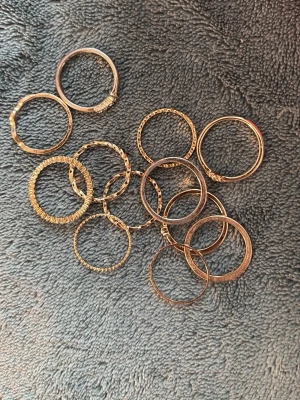 Ringar  - Säljer ett set med flera tunna ringar i guldfärg. Ringarna har olika mönster och texturer, vissa är släta medan andra har räfflade eller tvinnade detaljer. Helt oanvända! Ett riktigt värt köp, du kommer inte bli besviken💕 skriv om de finns några fler frågor eller fler bilder🌸💕