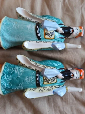 Retro kinesiska porslinsfigurer Vise män / Figurer – Par i porslin - Säljer ett par dekorativa och färgglada kinesiska porslinsfigurer i klassisk stil med vackert mönstrade klädnader i turkos, gult och blått. * Antal: 2 st * Material:** Handmålat porslin * Skick: Överlag väldigt fint skick, men observera att det finns mindre slitage/skada på staven/attributet som hålls i handen samt en märkning undertill (se bilder för egen bedömning av skicket). Vid övriga frågor skicka gärna meddelande. Lämnar självklart god omdömen om köparen gör det.