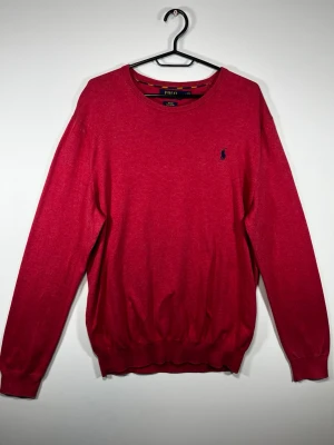 Polo Ralph Lauren Pima Cotton Tröja Röd – Slim Fit L - Klassisk röd stickad tröja från Polo Ralph Lauren i 100% Pima Cotton. Marinblå broderad Polo Pony-logga på bröstet.  • Storlek: L • Passform: Slim Fit • Material: 100% Pima Cotton • Färg: Röd • Broderad marinblå logga • Mjuk och bekväm kvalitet • Fint begagnat skick