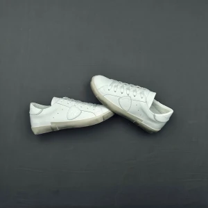 Vita Philippe model sneakers  - Stilrena vita Philippe Model skor med lågt skaft och klassisk siluett. Skorna är tillverkade i slätt läder med vita snören och diskreta sömdetaljer. Yttersulan är vit med en något använd look. Perfekta för en clean och enkel stil.