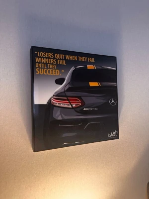 Tavla med Mercedes och citat - Säljer en modern tavla med motiv av en svart Mercedes AMG och ett inspirerande citat. Tavlan har en stilren design med tydliga linjer. Perfekt för bilälskare eller som cool inredningsdetalj.