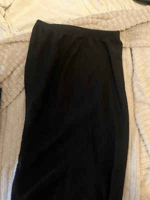 Sett Topp + Kjol - En svart lång kjol med enkel design och mjukt, lätt stretchigt tyg. Toppen är kort, det här settet funkar jätte bra på sommaren då det är tunt. Kjolen har en rak passform med slits. Perfekt att matcha med vad som helst. (kan köpas separat) 