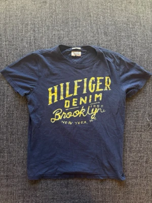Hilfiger denim T-shirt | vintage  - Hilfiger Denim T-shirt blå | st M | Snygg T-shirt i blå färg. Sällsynt och eftertraktad vintage modell som produceras ej längre och går knappt att få tag på. Vintage 2000’s modell. Perfekt nu till sensommaren/hösten 🏄 Kan även gå ner lite i pris vid snabb affär!