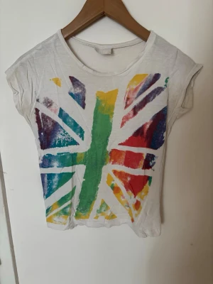 Vit t-shirt med färgglatt tryck - Säljer en vit t-shirt med korta ärmar och ett stort färgglatt tryck på framsidan🤍