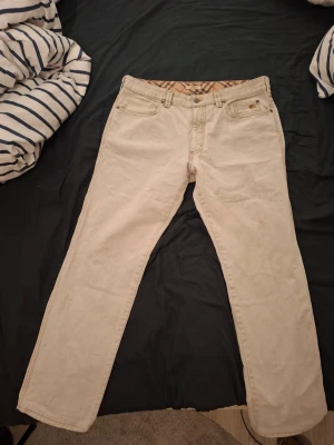 Gråa burberry jeans - Gråa burberry jeans i storlek 52 motsvarar ungefär W36 L32. Jeansen är använda men i väldigt bra skick förutom lappen på sista bilden. De passar bra om du är runt 180 och väger omkring 70-80kg