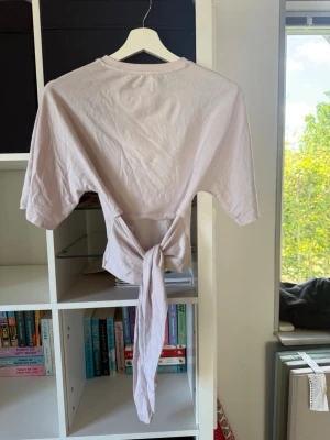Ljusrosa croppad topp med knyt - Säljer en rosa croppad topp med korta ärmar och långa knytband i ryggen. Toppen är från lager 157 men säljs ej längre. Använt fåtal gånger. Ryggen går att knyta till en fil rosett men tyvärr är jag otroligt dålig på att knyta..