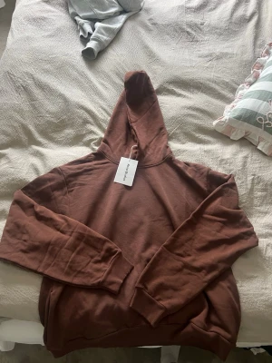 Brun hoodie från Acne Studios - Säljer en snygg brun hoodie från Acne Studios. Hoodien har en klassisk passform med huva och ribbade muddar vid ärmar och nederkant. Tillverkad i mjukt bomullsmaterial som känns skönt mot huden. Perfekt för en chill och stilren look.