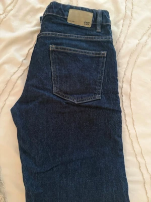 Mörkblå raka jeans från 157 - Säljer ett par mörkblå jeans från 157 med klassisk femficksdesign och raka ben. Jeansen har kontrastsömmar och knappgylf. Perfekta för dig som gillar en enkel och tidlös look.