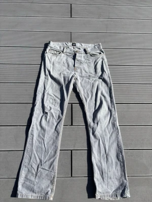 Ljusgrå raka jeans från Montén - Säljer ett par ljusgrå jeans från Montén i rak modell. Jeansen har klassisk femficksdesign, bälteshällor och kontrastsömmar. Perfekta för dig som gillar en avslappnad och stilren look.