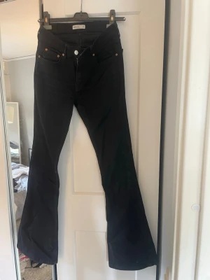 Svarta bootcut jeans från Perfect Jeans - Säljer ett par svarta bootcut jeans från Perfect Jeans i storlek 36. Jeansen har klassisk femficksmodell, hög midja och utsvängda ben. Snygga kopparfärgade nitar och knappdetaljer. Materialet är stretchigt och bekvämt.
