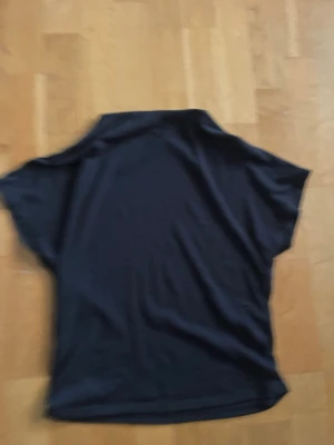Svart polotopp med korta ärmar - En enkel svart polotopp med korta ärmar och lös passform. Perfekt att styla till jeans eller kjol för en clean look. Tillverkad i mjukt bommulsmatrial   som känns skönt mot huden.