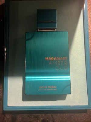 Haramain Amber Oud Aqua Dubai parfym 75ml - 75ml kvar Exklusiv parfymflaska i metalliskt turkos med guldtext från Haramain. Flaskan har en modern, rektangulär form och elegant lock. Doften heter Amber Oud Aqua Dubai och flaskan levereras i en matchande ask. 