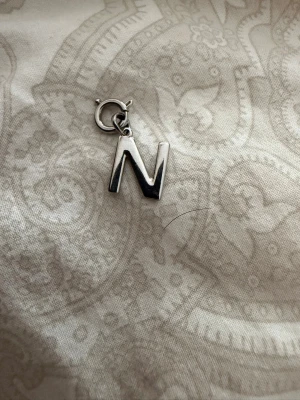 Berlock i form av bokstaven N - Barlock i silverfärgad metall med bokstaven N med hänge till fästa i barlock armband och halsband från Edblad aldrig använt de 