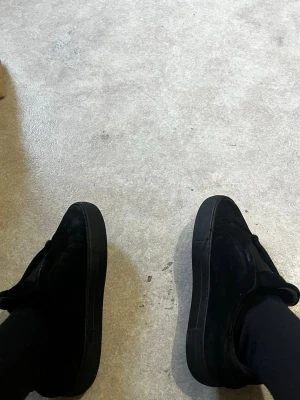 Svarta sneakers från Axel Arigato - Säljer ett par helsvarta sneakers från Axel Arigato i mocka. Skorna har en clean och stilren design med tjock sula och lågt skaft. Perfekta för dig som gillar minimalistisk stil och vill ha något som funkar till det mesta.