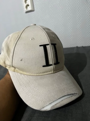Beige keps les deux  - Snygg beige keps i bomull med svart broderad II-logga framtill och små broderade detaljer i blått, vitt och rött på sidan. Klassisk böjd skärm och justerbar passform. Perfekt för en avslappnad streetwear-look.