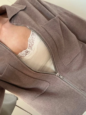 Brun zip hoodie med stora fickor - Mysig brun hoodie med dragkedja framtill och två stora fyrkantiga fickor på bröstet. Tillverkad i ett mjukt, stickat material som känns skönt mot huden. Perfekt för en avslappnad och chill stil.