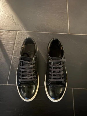 Lanvin Cap toe skor - Snygga svarta sneakers i läder-look med klassisk vit sula och svarta skosnören. Modellen är låg och har en stilren design som passar till det mesta. Perfekta för dig som gillar en clean och enkel stil.