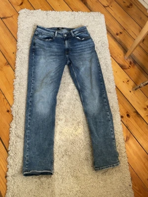 Blå jeans 521 Tapered Fit 31/30 - Säljer ett par blå jeans i modellen 521 Tapered Fit. Jeansen har klassisk femficksdesign, normalhög midja och avsmalnande ben. Snygg tvätt med slitningar och kontrastsömmar. Perfekta för en avslappnad och trendig look.