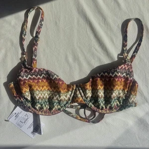 Glittrig mönstrad bikini - Superfin glittrig bikinitopp i ett grön/beige/guldigt missoni-liknande mönstret. Den har guldiga detaljer och bygel.   Modellen ”Elegant Ethnic”  Köpt för 559kr och är helt slutsåld💚🤍🤎