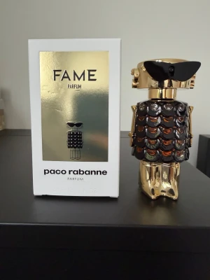 Paco Rabanne Fame Parfum - Rabanne Fame Parfum (50 ml) är en rik, glamorös och förförisk doft. Den öppnar med fruktig mango och bergamott, har ett hypnotiskt hjärta av jasmin och rökelse och landar i en sensuell bas av mysk och sandelträ. Flaskan är på 50 ml och endast några enstaka spray har använts.