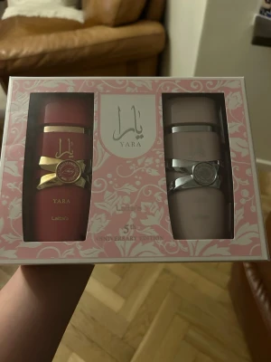 Lattafa Yara parfymset - Exklusivt parfymset från Lattafa med två flaskor: Yara och Yara Candy. Ena flaskan är matt röd med gulddetaljer och den andra är ljusrosa med silverdetaljer. Båda flaskorna har elegant design och rymmer 100 ml vardera. Perfekt present till någon som älskar lyxiga dofter. Nya och oöppnade