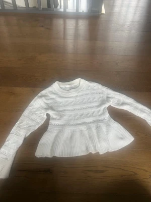 Vit stickad tröja från Gina Tricot - Supersöt vit tröja från Gina Tricot med rund halsringning och fina kabelstickade detaljer. Tröjan har lång ärm och en lätt utsvängd, ribbad nederdel som ger en snygg siluett.❤️