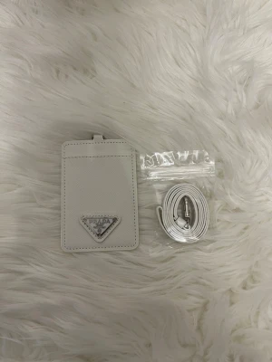 Korthållare i vit med band  - Säljer en helt nytt korthållare i vit  med band, passar med allt och är bra om man har mobilförbud i skolan 