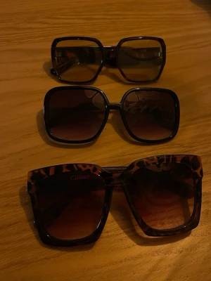 Tre par fyrkantiga solglasögon - Säljer tre par solglasögon med stor, fyrkantig form. Ett par har svart båge, ett par har mörkbrun båge och det tredje paret har leopardmönstrad båge med bruna glas. Perfekt accessoar för att lyfta din stil i sommar.