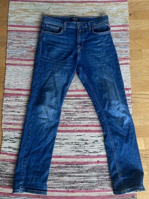 Replay jeans slim fit - Snygga blå slim fit jeans med lätt slitna detaljer och klassisk femficksdesign. Jeansen har normal midja, raka ben och kontrastsömmar. Tillverkade i ett mjukt denimtyg som ger en bekväm känsla och passar perfekt till vardagslooken. Jeansen är 38cm i bredd och 98cm i längd
