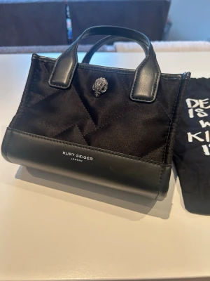 Kurt Geiger London extra small recycled shopper bag - Super söt miniväska som jag har använt ett par gånger men som knappt har några tecken på användning. Axelrems bandet ingår och är aldrig använt, samma med dustbagen som den kom i, nypris: 950kr. Skriv om ni har några frågor eller vill ha mer bilder!☺️Ligger även uppe på Vinted💗