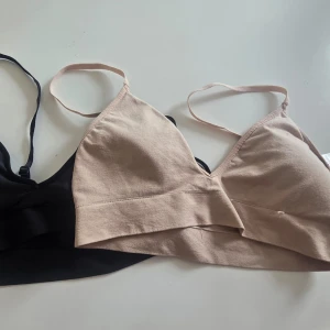 Två mjuka bhar i svart och beige - Säljer två mjuka bhar utan bygel, en i svart och en i beige. Båda har smala axelband och trekantsformade kupor. Perfekta för dig som gillar bekväma och enkla underkläder i basic färger.