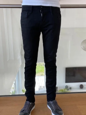 Svarta slim fit jeans herr - Säljer ett par svarta slim fit jeans med klassisk femficksdesign och dragkedjegylf. Jeansen har smal passform och är tillverkade i ett stretchigt material som sitter snyggt. Perfekta till sneakers och t-shirt för en clean look.