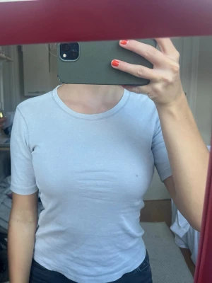 Vit basic t-shirt med kort ärm - En enkel och stilren vit t-shirt med rund hals och korta ärmar. Modellen är figurnära och passar perfekt till jeans eller kjol. Tillverkad i mjuk bomull som känns skön mot huden.