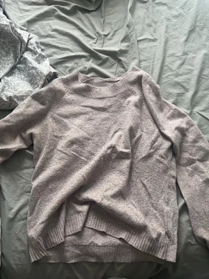 Ljusgrå stickad tröja - En enkel och stilren stickad tröja med rund halsringning och ribbade muddar vid ärmslut och nederkant. Perfekt för lager på lager och passar till det mesta i garderoben. Mjuk och skön känsla i materialet.