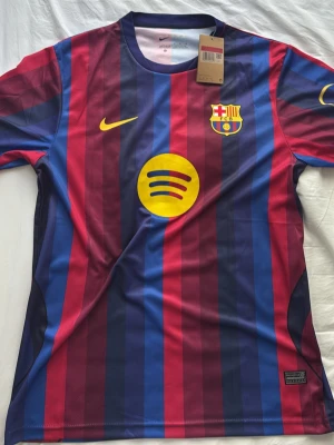 Barcelona matchtröja Lamine Yamal #10 - Säljer en officiell FC Barcelona matchtröja från Nike med Lamine Yamal och nummer 10 på ryggen. Tröjan har klassiska blå och röda vertikala ränder, gula detaljer och klubbmärke på bröstet. Tillverkad i lätt och ventilerande material, perfekt för fotboll eller träning.