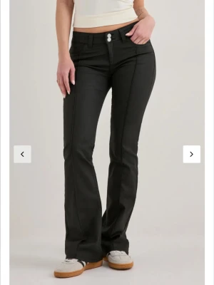 Svarta bootcut jeans med low waist - Snygga svarta jeans med bootcut passform och low waist. Jeansen har dubbla knappar framtill, markerade sömmar och klassiska fickor både fram och bak. Materialet är lite stretchigt och i storlek 36/short. Köpte från Nelly för ett årsen och använda ett fåtal gånger. Köpta:699kr Säljer:400kr 