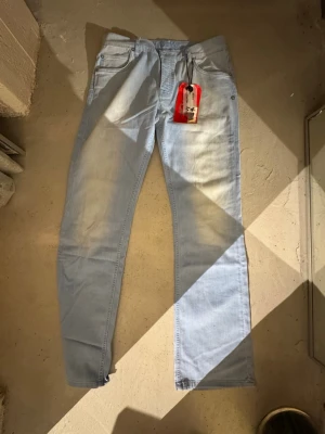 Ljusblå raka jeans herr - Säljer ett par ljusblå jeans med rak passform och klassisk femficksdesign. Jeansen har en modern tvätt och är tillverkade i ett mjukt denimtyg. Perfekta för en avslappnad och trendig stil. Passar dig som gillar enkel och stilren look. Finns att hämta i Gröndal.