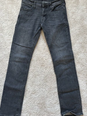 Mörkgrå slim jeans - Snygga mörkgrå jeans med slim passform och klassisk femficksdesign. Jeansen har subtila slitningar och kontrastsömmar. Tillverkade i ett mjukt och bekvämt denimtyg. W29, L32