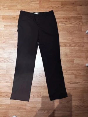 Svarta kostymbyxor från Zara - Stilrena svarta kostymbyxor från Zara med klassisk rak passform och hällor för bälte. Perfekta för en clean och snygg look. Byxorna är tillverkade i ett mjukt och bekvämt tyg som ger en dressad känsla.