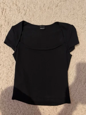 Svart topp från Gina Tricot - En enkel och stilren svart topp från Gina Tricot med korta ärmar. Perfekt att matcha med jeans eller kjol eller spicy up till en middag ute.