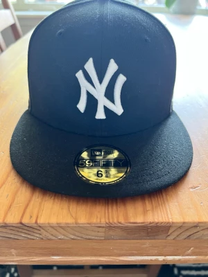 Svart New Era Yankees keps 59FIFTY - Säljer en svart New Era 59FIFTY keps med New York Yankees-logga broderad i vitt framtill🤩Klassisk flat brim och autentisk sticker kvar på skärmen. Perfekt för dig som gillar streetwear och sportig stil😅