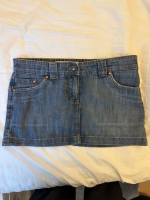 Kort jeanskjol från TRF Denim - En snygg kort jeanskjol från TRF denim med snygga bruna detaljer på bakfickorna💕 Midjemåttet är ca 47cm och den är ca 27cm lång