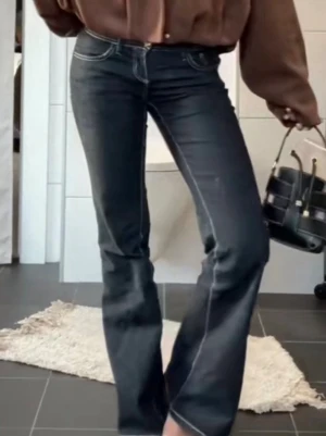 Gina tricot jeans - Snygga mörkblå bootcut jeans med vita kontrastsömmar och klassisk femficksmodell. Jeansen har hög midja och lätt utsvängda ben, vilket ger en trendig siluett. Perfekta att matcha med en oversized tröja eller crop top.
