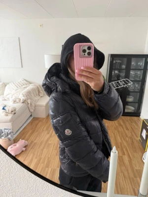 Marinblå Maya jacka  - Säljer en marinblå Maya moncler pufferjacka med hög krage och avtagbar huva. Jackan har dragkedja framtill, två sidofickor och quiltad design som ger en riktigt snygg och puffig look. Perfekt för kalla dagar och enkel att matcha med olika outfits. Ser lite skrynklig ut pga den ha legat i vakumpåse. Storlek 14 passar mig som bruka ha S. Jackan ha inga defekter då den ha tagits hand om väl och varit väldigt försiktig. Har tyvärr inget kvitto kvar men köpt på nk i Göteborg. 
