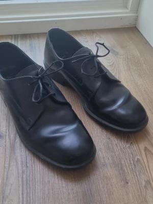 Svarta vintage finskor från Norröna - Ett par svarta finskor från Norröna. Marerialet är i skinn. Skorna har snörning framtill och en slät design. Tillverkade i Norge. Skorna är använda, bilder finns som visar de små skavanker som uppstått